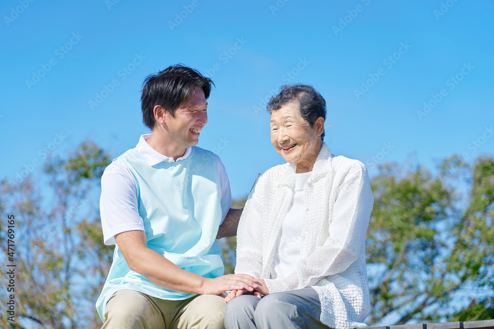 介護士と高齢者　屋外