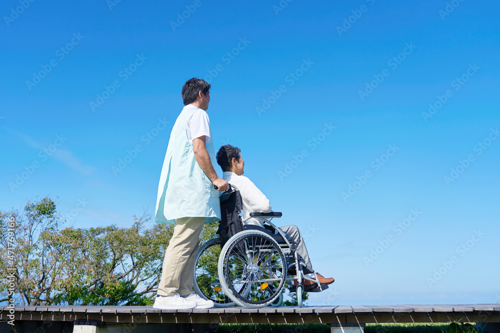 介護士と車椅子に乗る高齢者　屋外