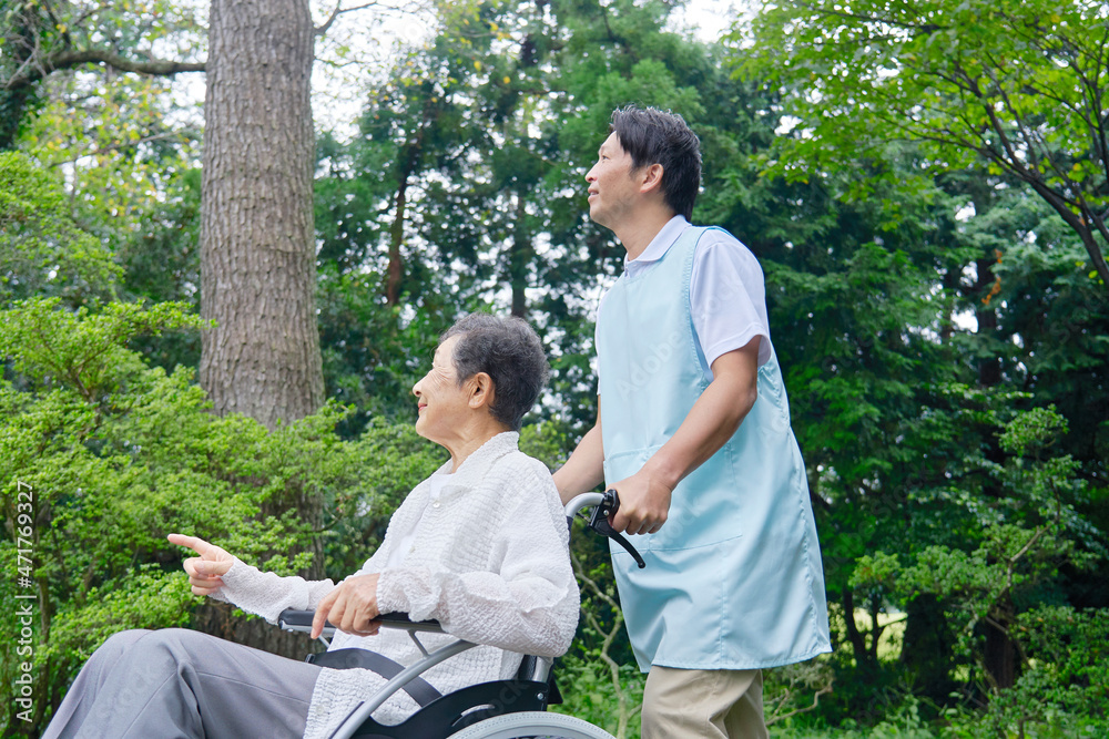 介護士と車椅子に乗る高齢者　屋外