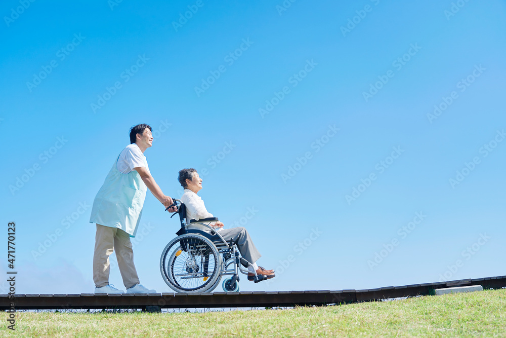 介護士と車椅子に乗る高齢者　屋外