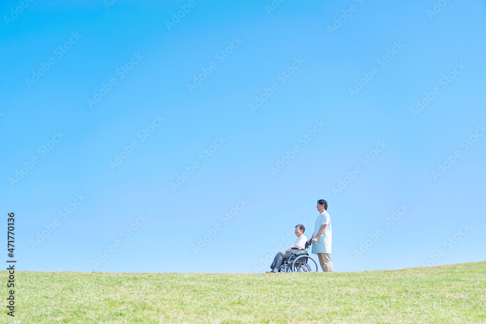 介護士と車椅子に乗る高齢者　屋外