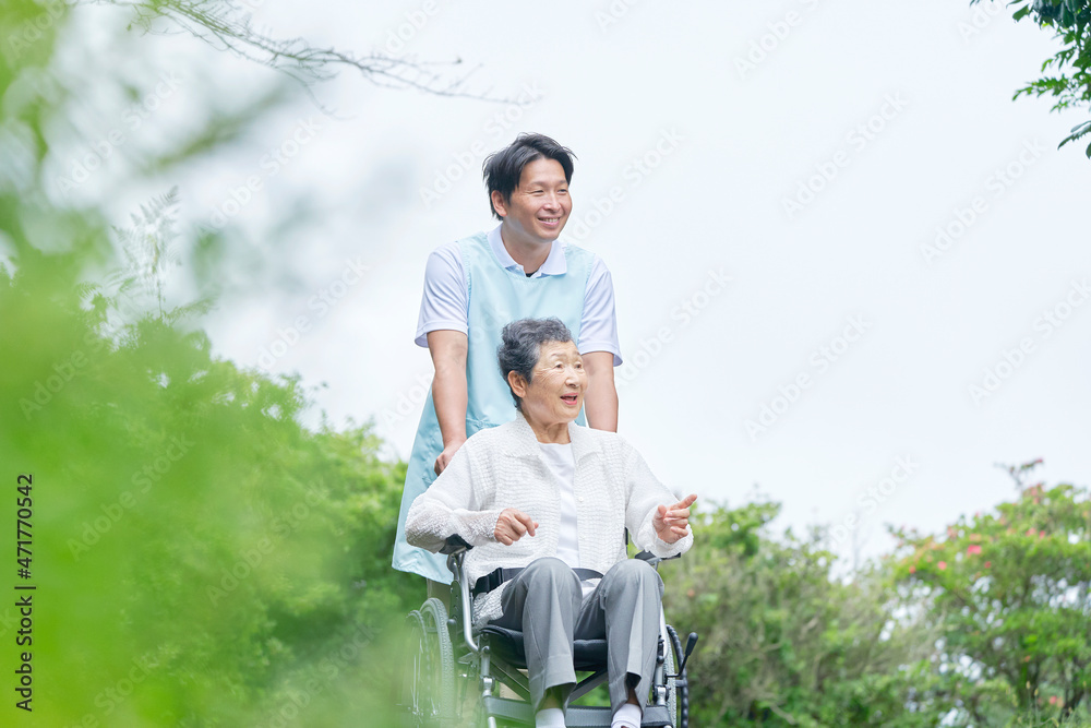 介護士と車椅子に乗る高齢者　屋外