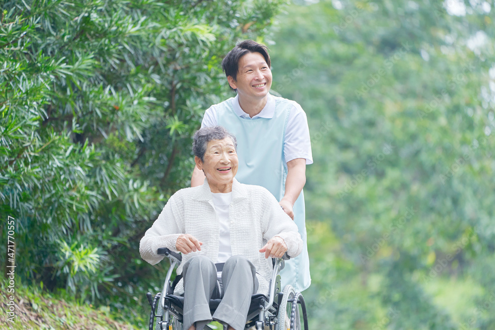 介護士と車椅子に乗る高齢者　屋外