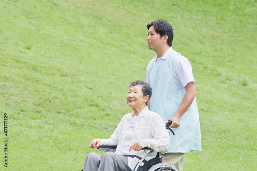 介護士と車椅子に乗る高齢者　屋外