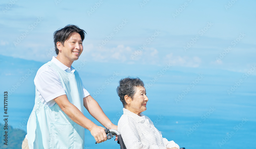 介護士と車椅子に乗る高齢者　屋外