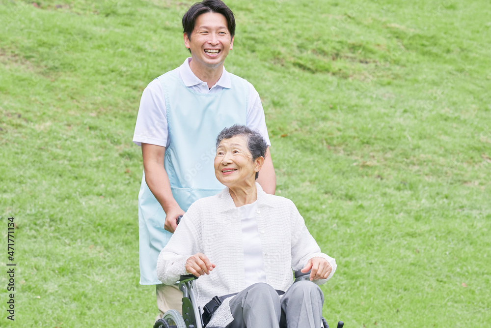 介護士と車椅子に乗る高齢者　屋外