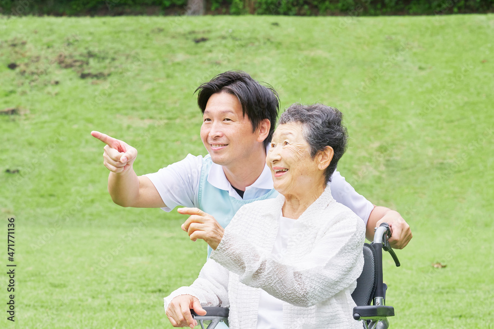 介護士と車椅子に乗る高齢者　屋外