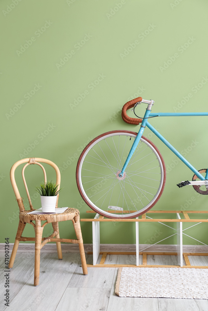 Chair with houseplant, stand and bicycle near green wall