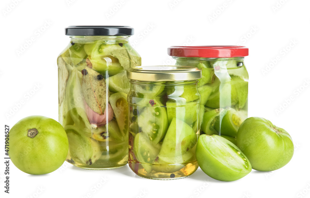 Jars with canned green tomatoes on white background