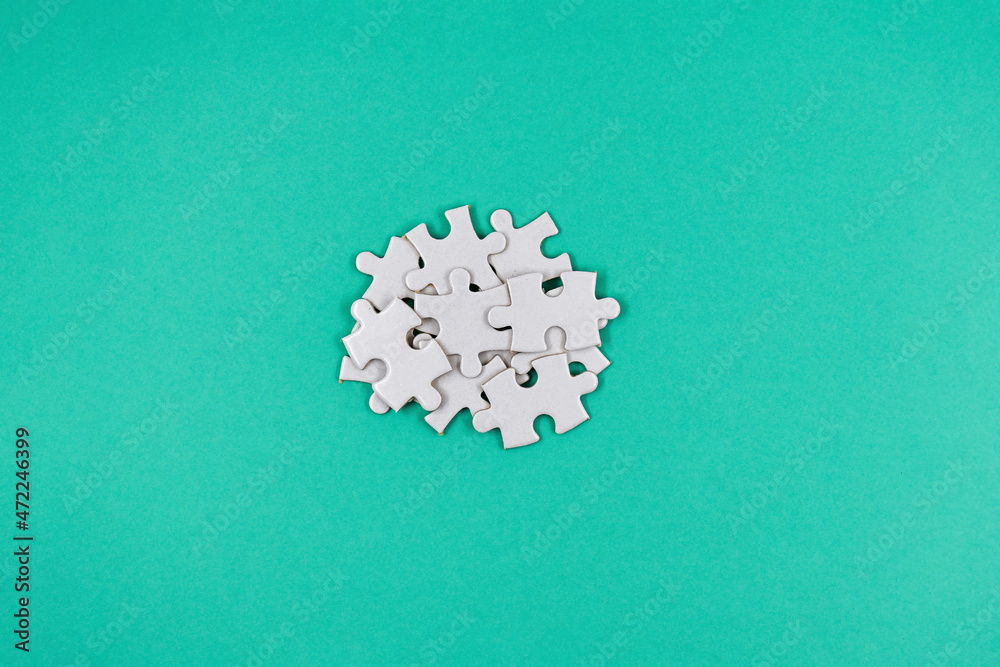 Bunch of puzzle pieces lying on a paper blue background