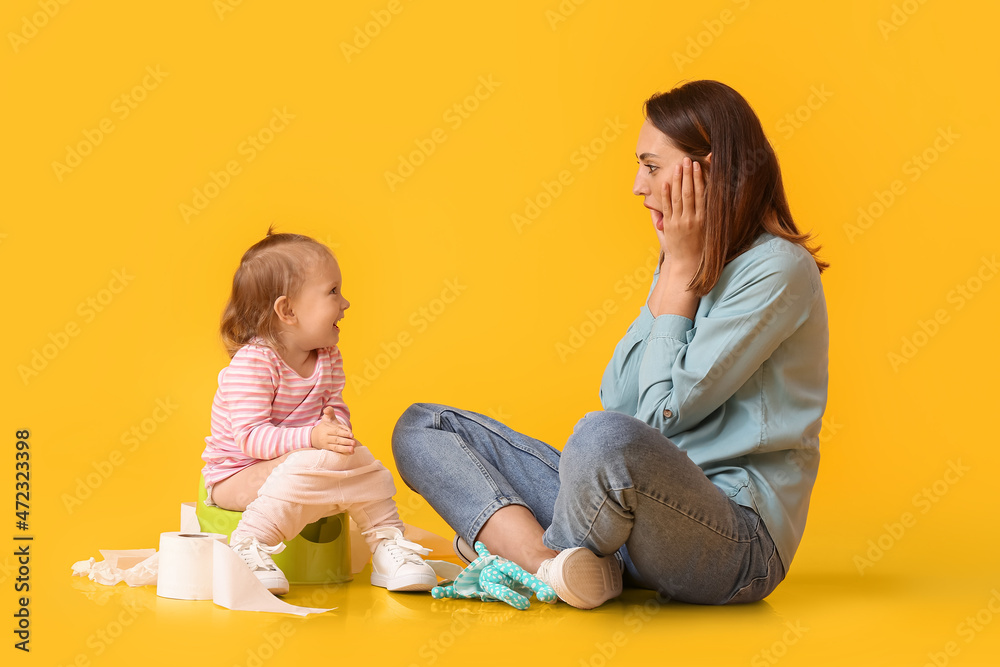 Mother potty training her little daughter on color background