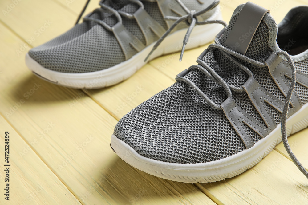 Sportive shoes with laces tied in bow on color wooden background, closeup