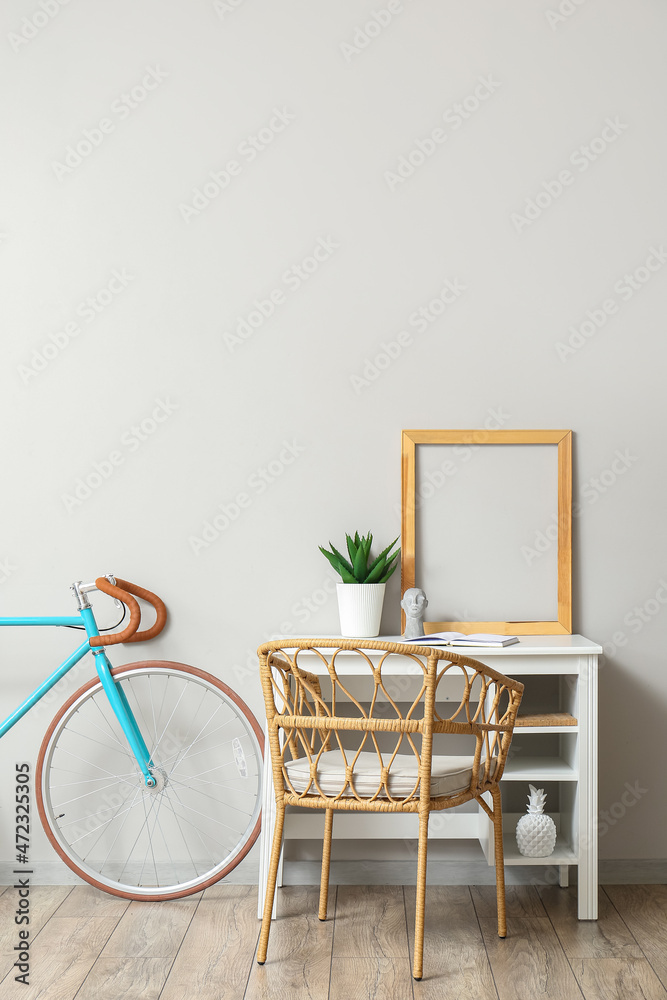 Modern workplace with frame and bicycle near light wall