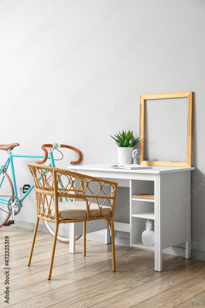 Modern workplace with frame and bicycle near light wall