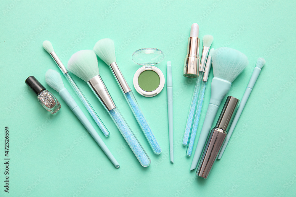 Set of decorative cosmetics with makeup brushes on color background