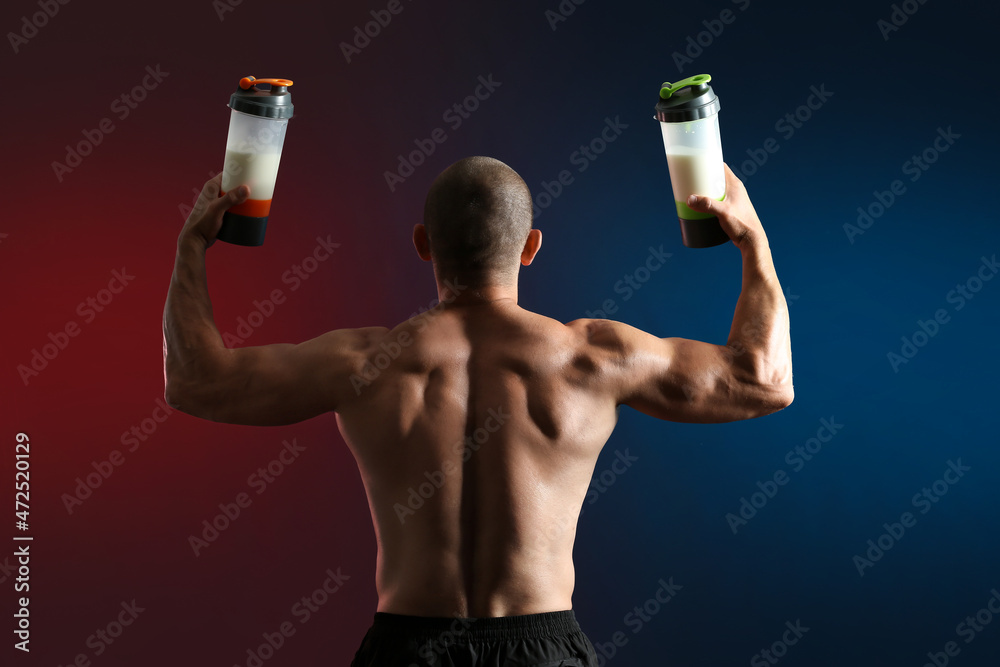 Male bodybuilder with protein shakes on dark background, back view