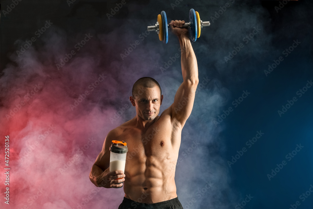 Male bodybuilder with protein shake and dumbbell on dark background