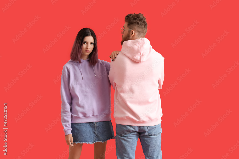 Cool young couple in hoodies on color background