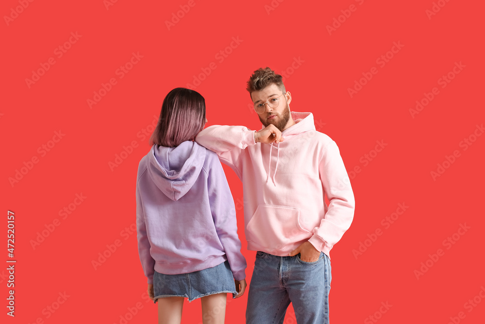 Cool young couple in hoodies on color background