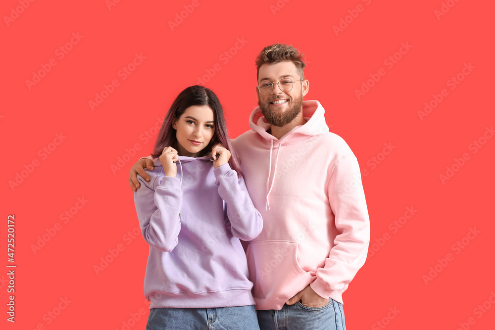 Cool young couple in hoodies on color background