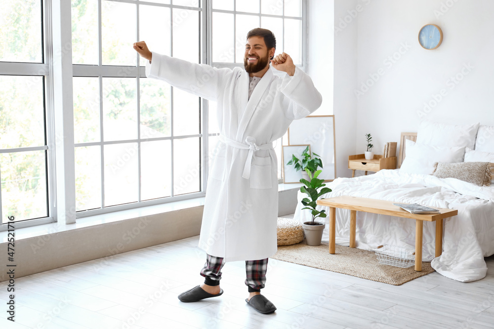 Handsome man in bathrobe dancing at home