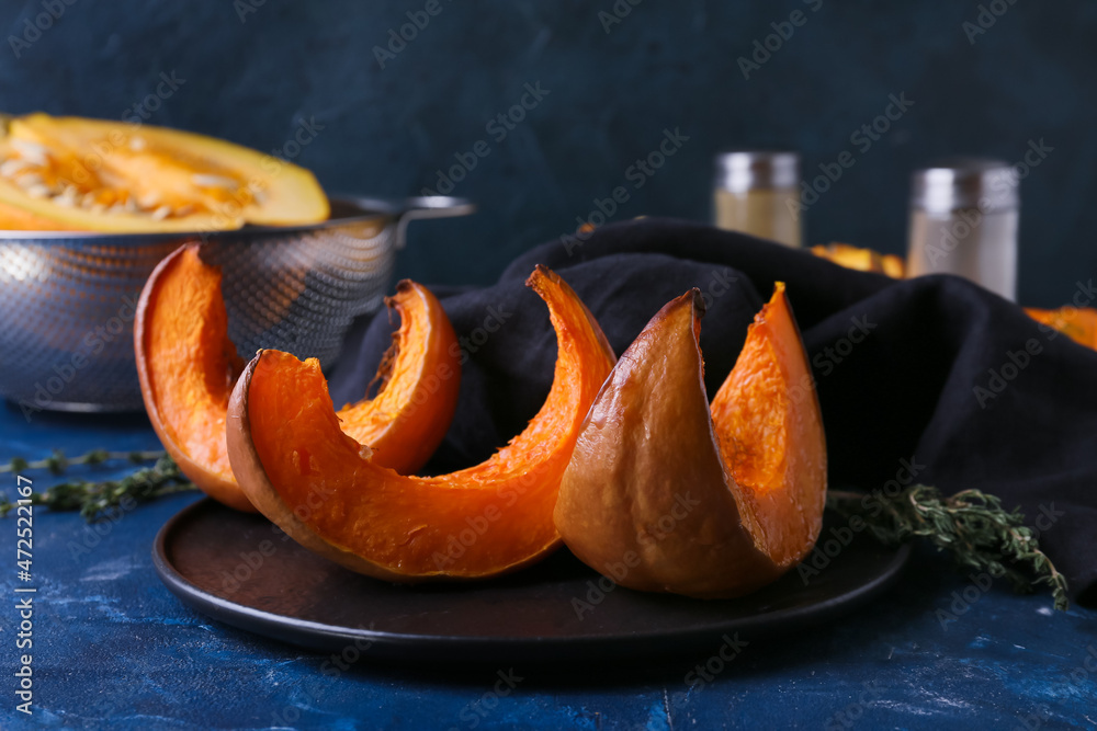 Plate with baked pumpkin pieces on table