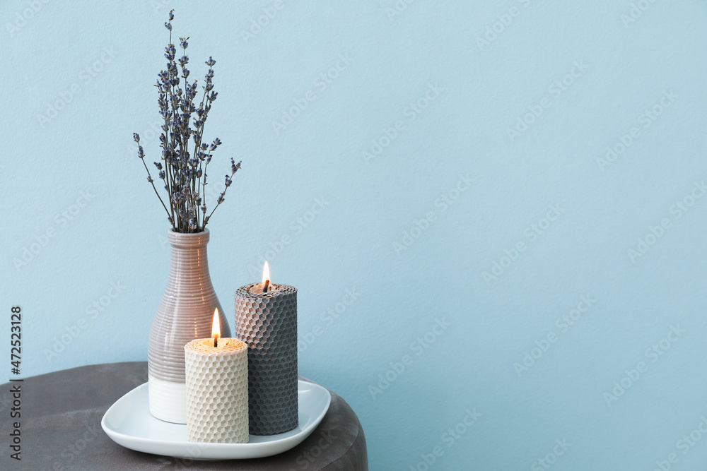 Composition with glowing candles on pouf in room