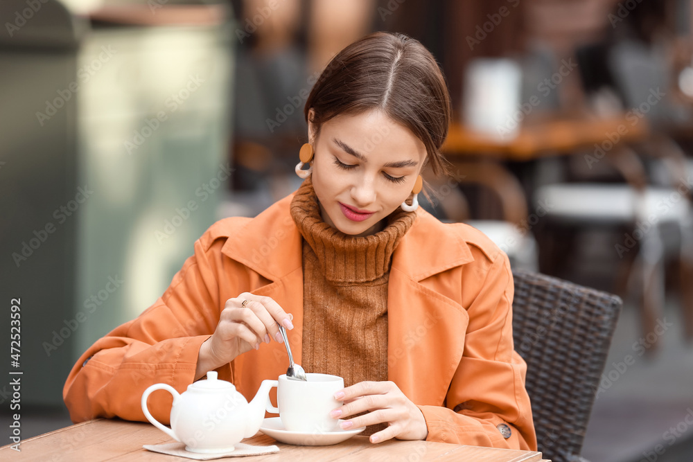 Beautiful woman stirring tea in street cafe