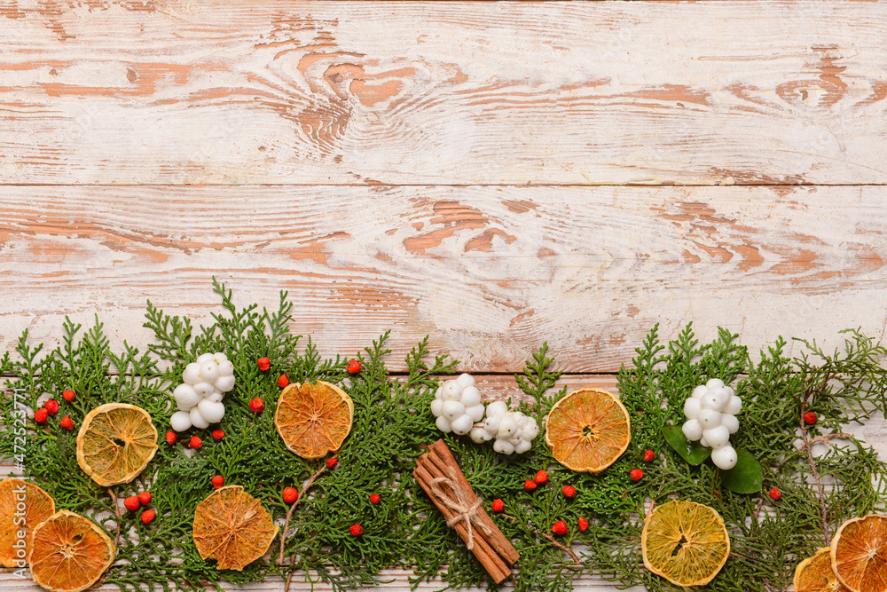 Composition with thuja branches and dried orange slices on light wooden background