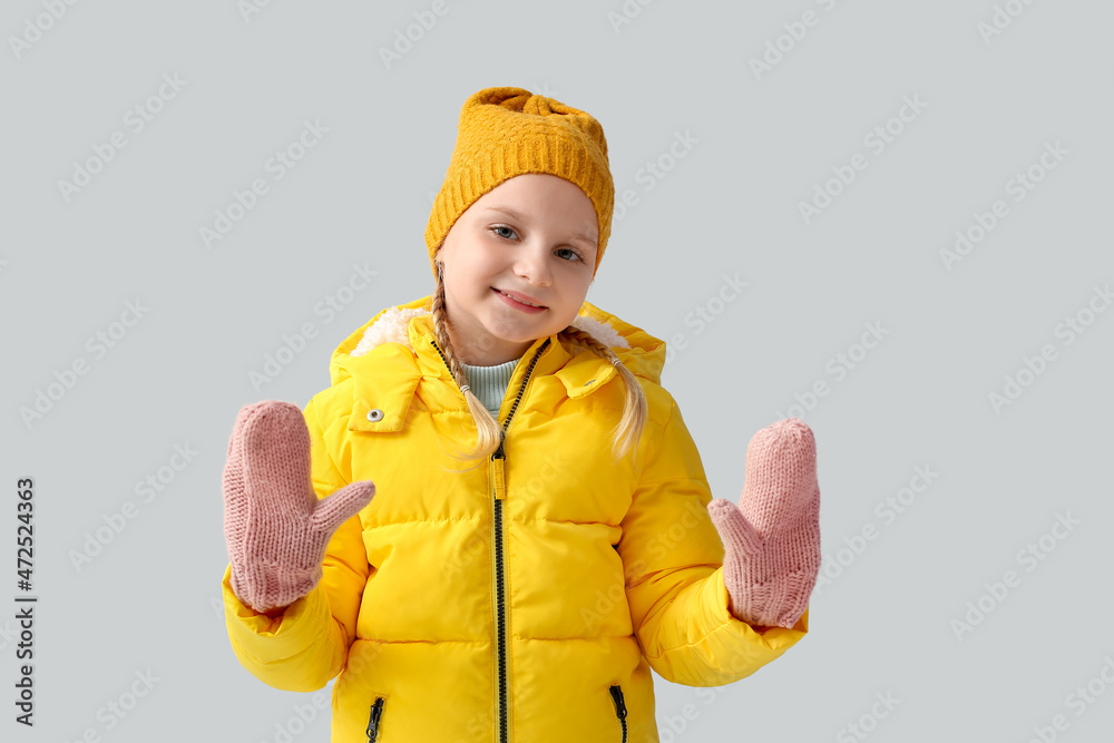 Little girl in stylish winter clothes on light background