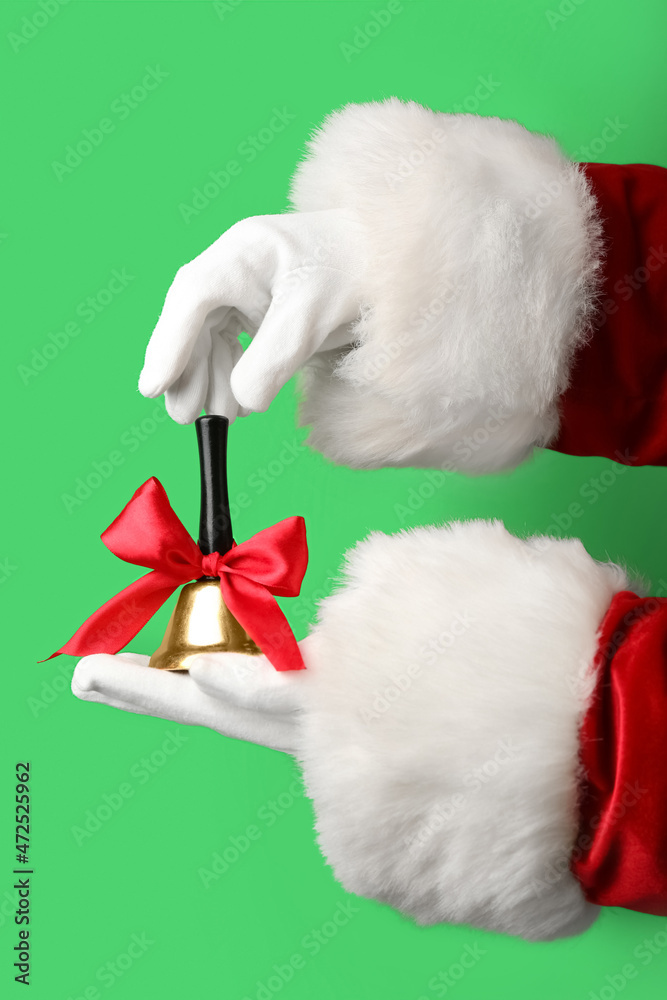 Santa hands with Christmas bell on green background, closeup