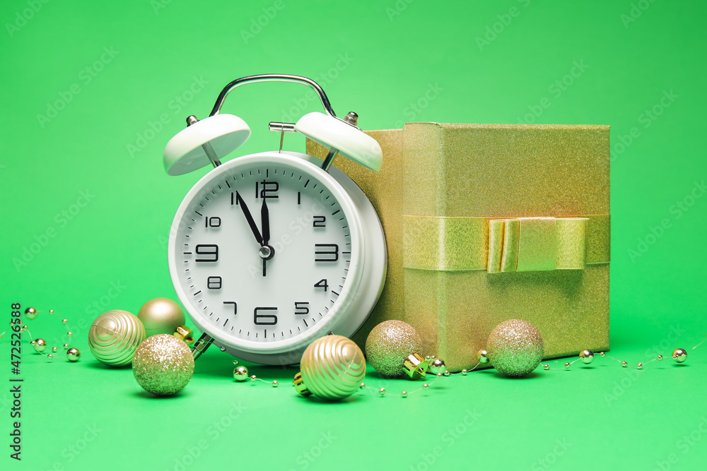 Alarm clock, Christmas gift and decorations on green background