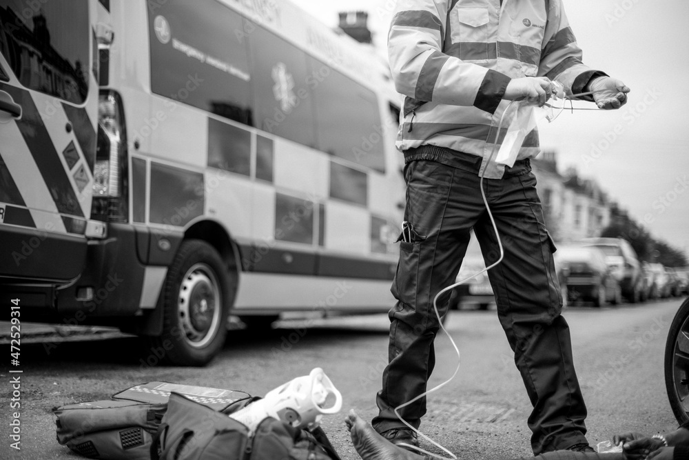 Male paramedic preparing an oxygen mask to an injured woman on a road