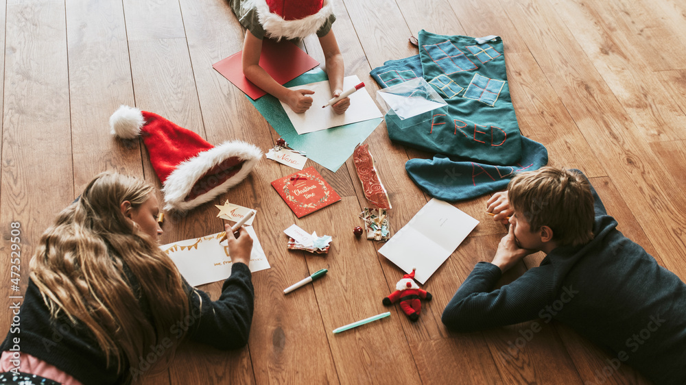 Kids writing Christmas cards on wooden floor