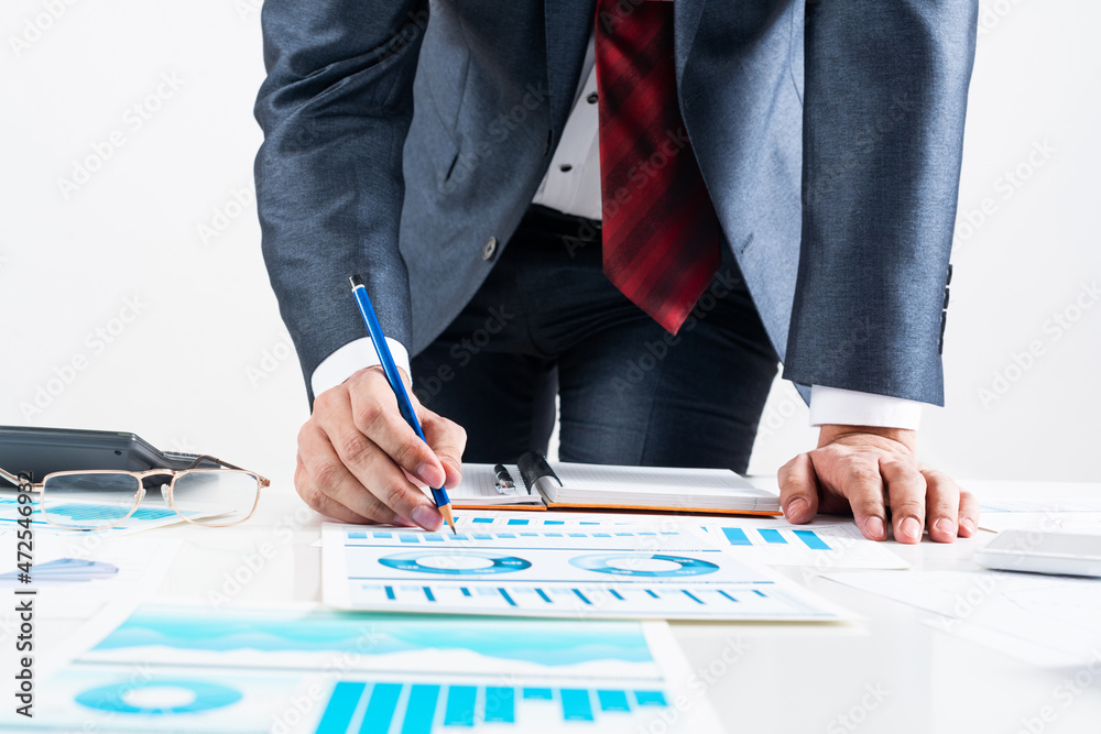 Businessman standing near office desk with pen