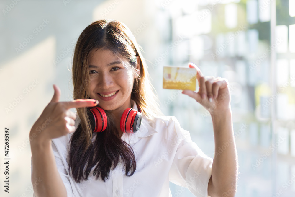 快乐微笑的女孩，手里拿着一张信用卡。