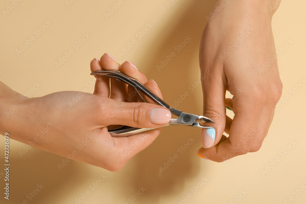 Woman doing manicure on beige background