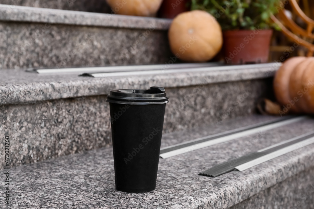 Takeaway cup of tasty latte on stairs outdoors