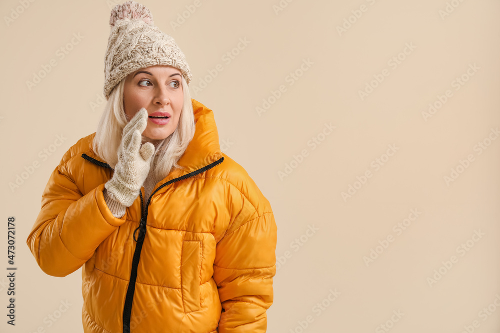 Beautiful mature woman in winter clothes on color background