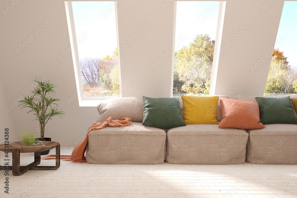 Stylish room in white color with sofa and autumn landscape in window. Scandinavian interior design. 