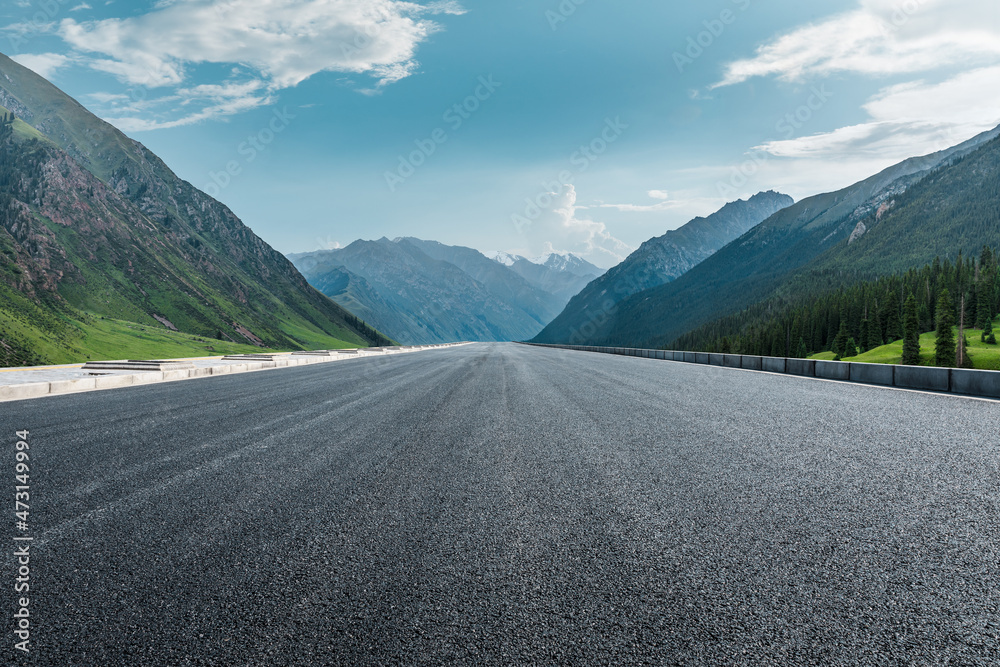 笔直的柏油路和蓝天下的山。公路和山的背景。