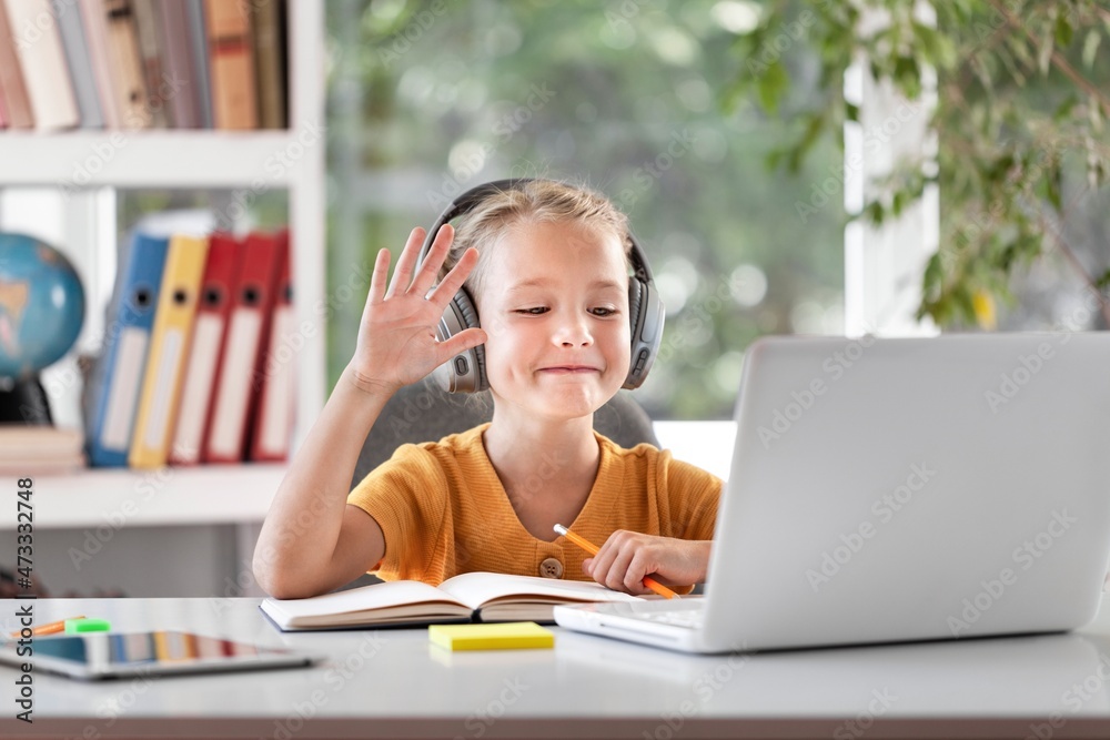 Smiling little child in headphones have a video call distant class using a laptop