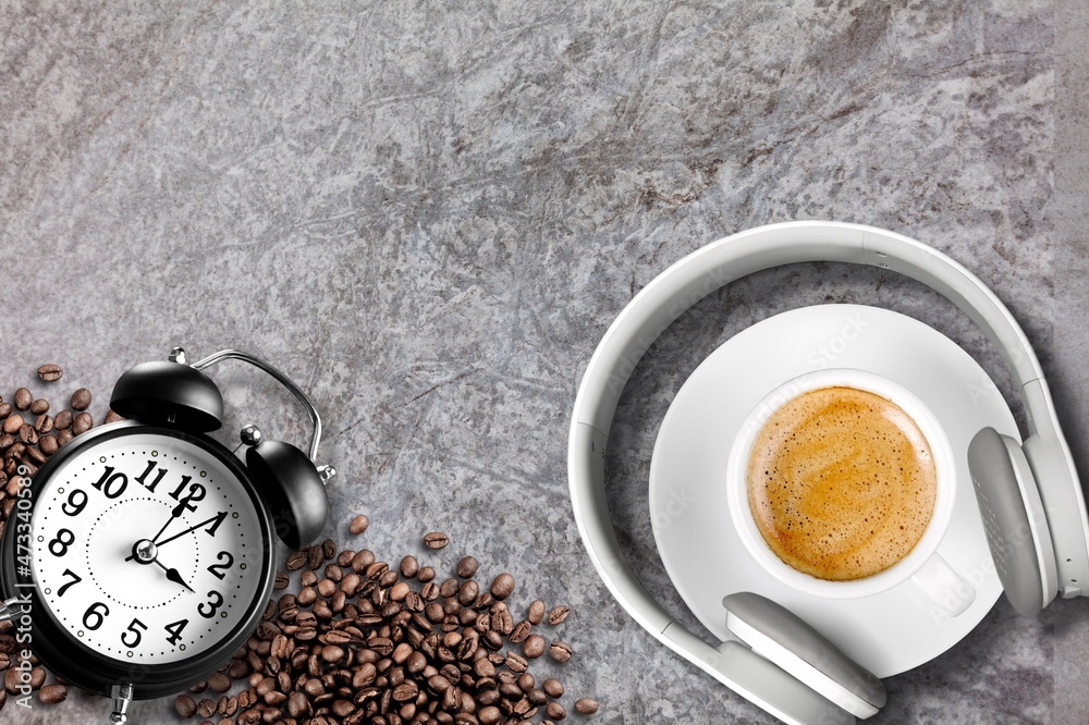 Hot coffee mug with headphones in vintage style and coffee beans on the desk.