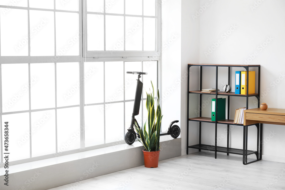 Interior of light office with shelving unit and bike