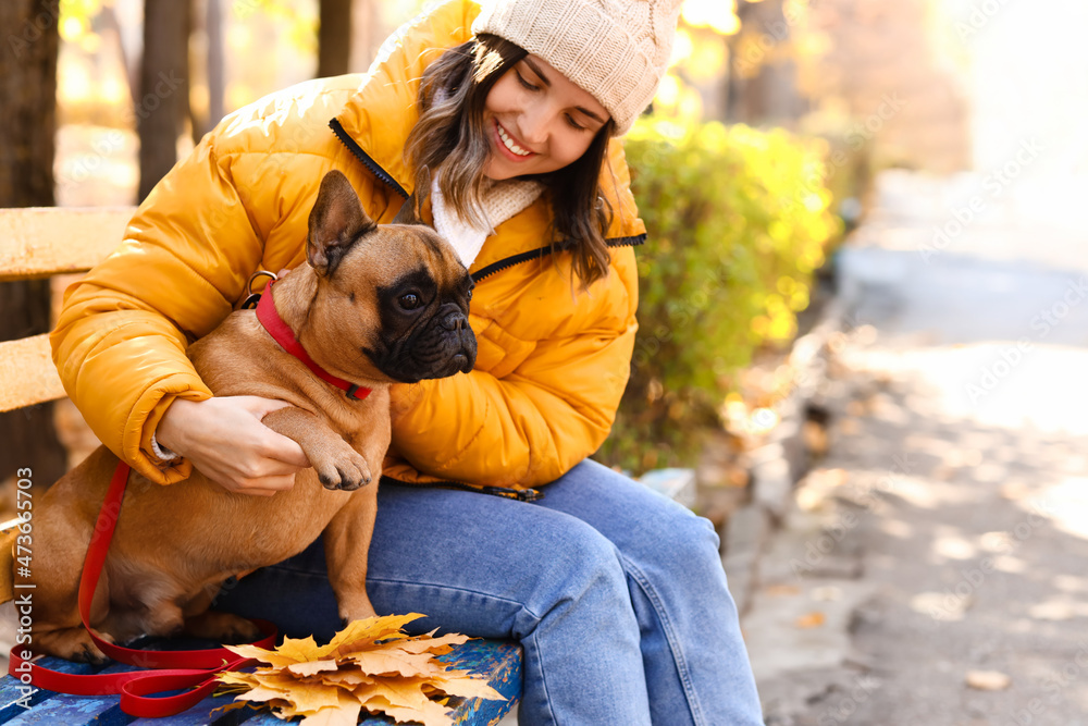 年轻女子与可爱的法国斗牛犬在秋季公园