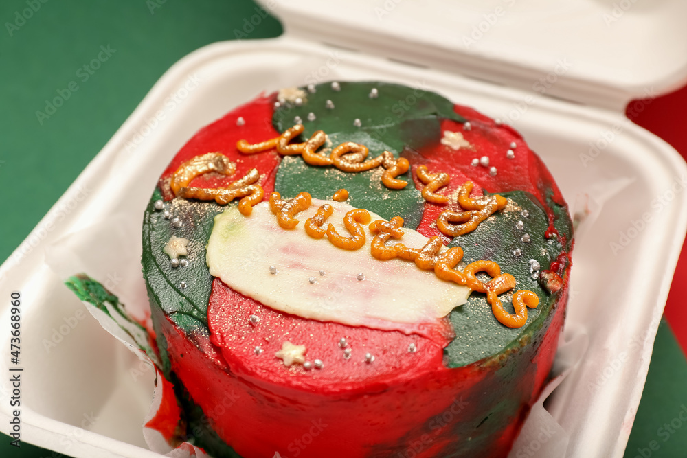 Plastic lunch box with Christmas bento cake on color background, closeup