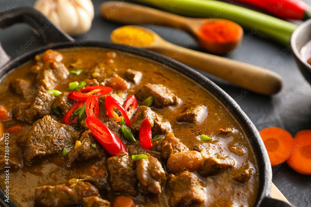 Dish with tasty beef curry on dark background, closeup