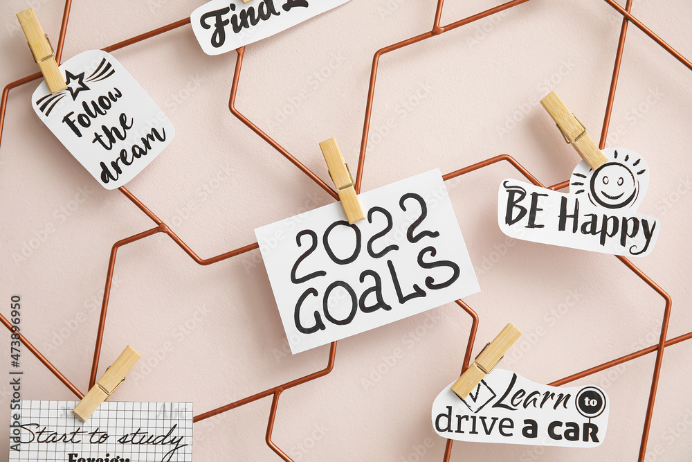 Paper sheets with written figure 2022 and goals pinned to moodboard on color background, closeup