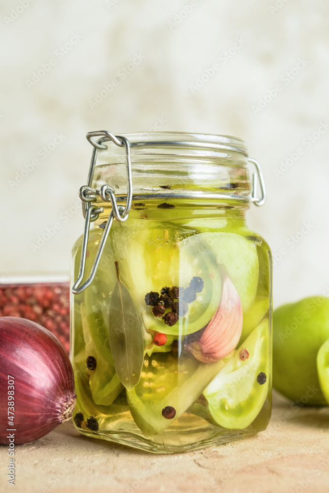 Jar with canned green tomatoes on table