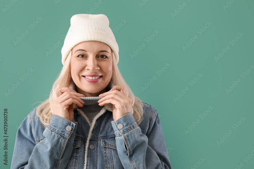 Beautiful mature woman in warm clothes on color background